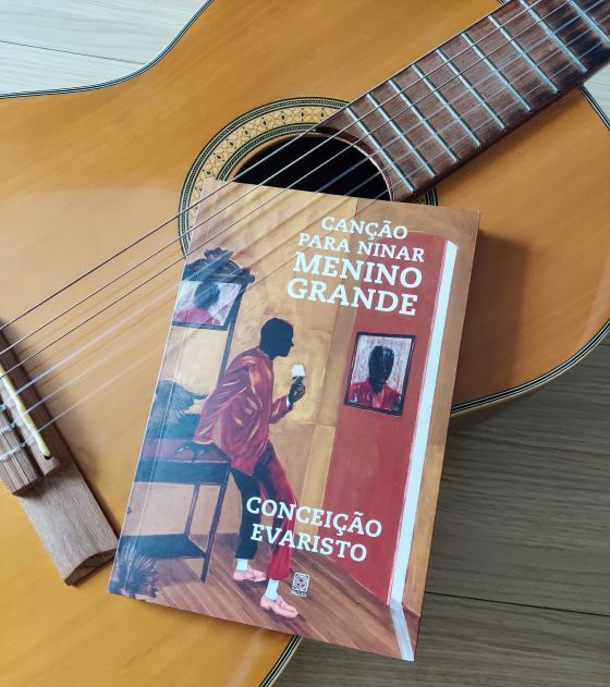 Na foto, posicionado sobre um violão, está o livro intitulado "Canção para ninar menino grande", da autora Conceição Evaristo.